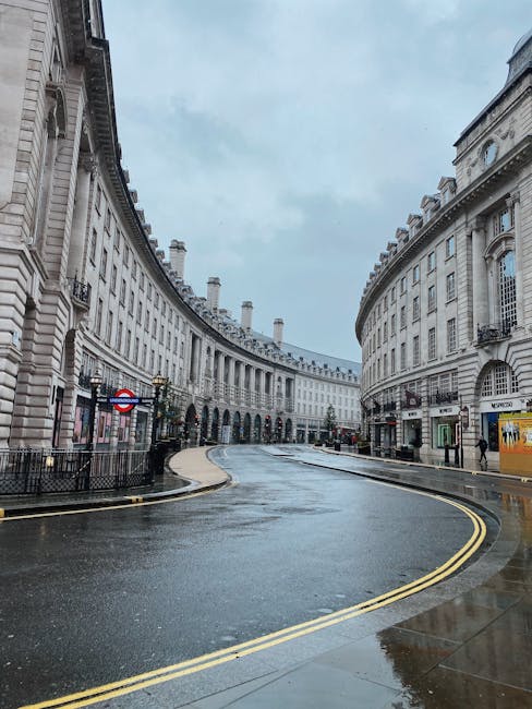 The image depicts a deserted, curved street in a historic London district, lined with elegant, classical-style white stone buildings featuring ornate architectural details and tall windows. The street